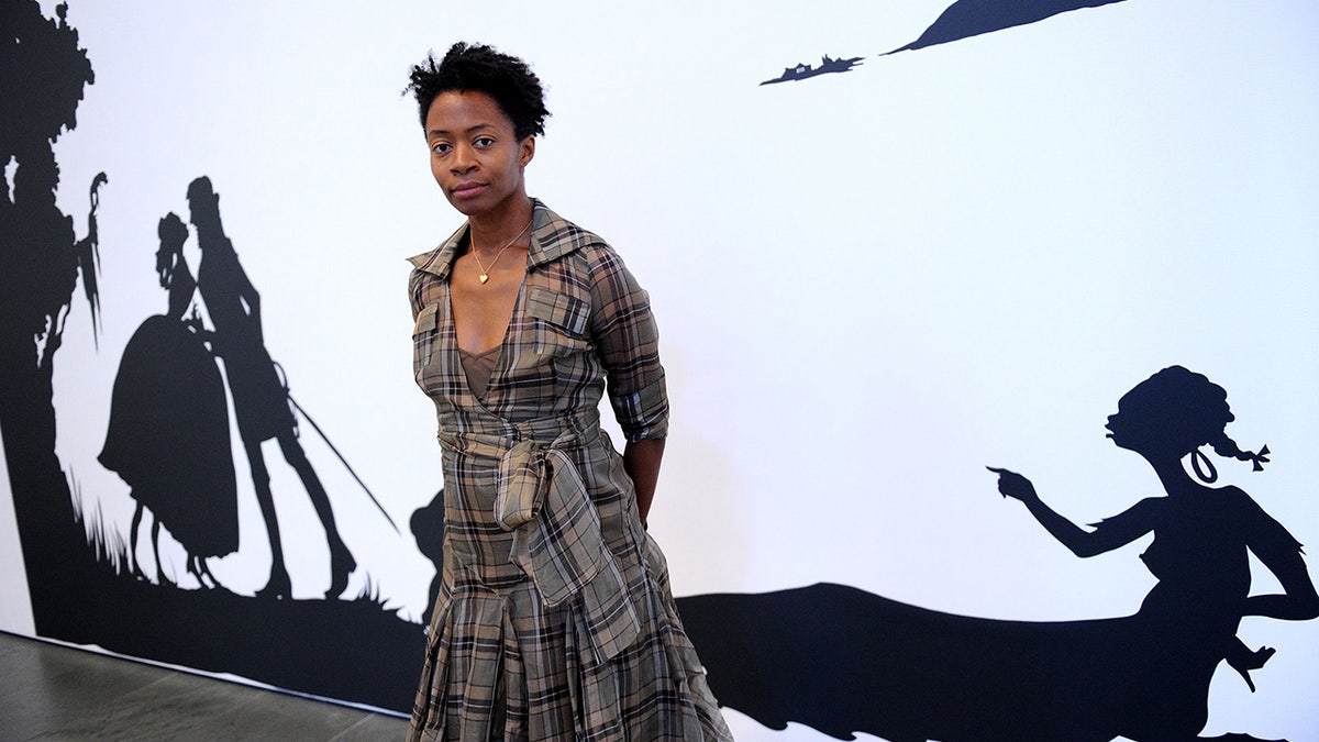 The artwork assigned to the class, by Kara Walker, is titled "Gone: An Historical Romance of a Civil War as It Occurred b'tween the Dusky Thighs of One Young Negress and Her Heart." Walker is shown here in front of a portion of that piece, attending the opening reception for the reinstallation of contemporary art from the collection at MOMA on June 29, 2010 in New York, City.