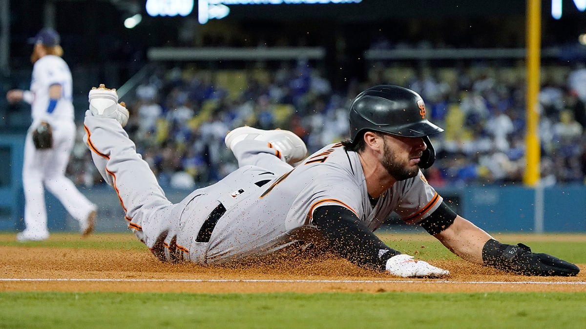 The San Francisco Giants' Kris Bryant slides safely into third base on a single by LaMonte Wade Jr. during the second inning of Game 4 of a baseball National League Division Series against the Los Angeles Dodgers, Tuesday, Oct. 12, 2021, in Los Angeles.