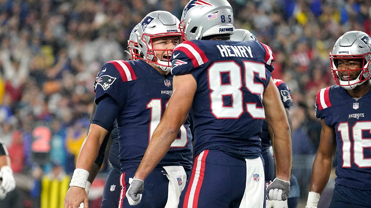 New England Patriots quarterback Mac Jones, left, celebrates after his touchdown pass to tight end Hunter Henry (85) during the first half of an NFL football game against the Tampa Bay Buccaneers, Sunday, Oct. 3, 2021, in Foxborough, Mass.