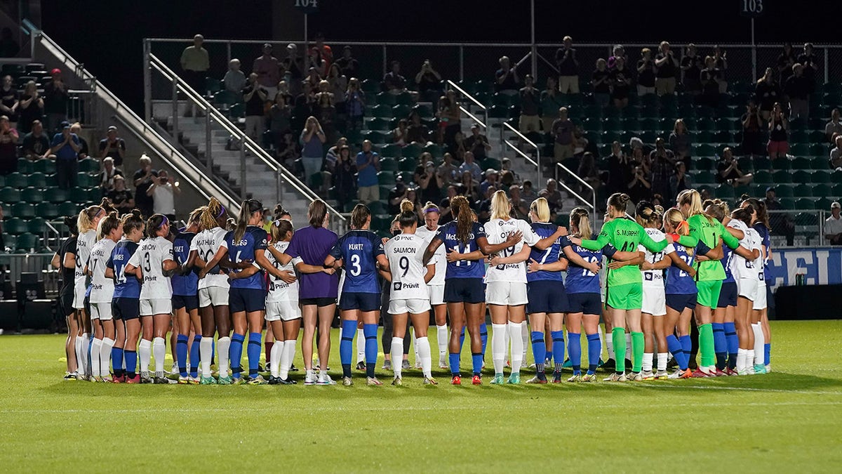 North Carolina Courage and Racing Louisville FC players pause and gather at midfield during the first half of an NWSL soccer match in Cary, N.C., Wednesday, Oct. 6, 2021.