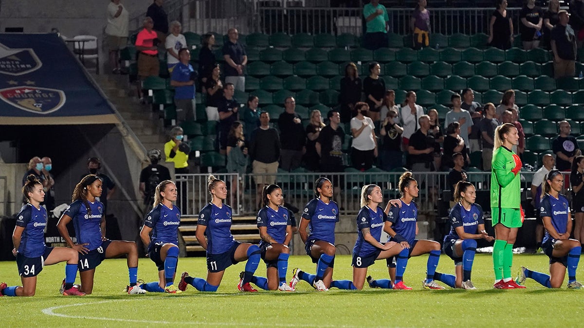 North Carolina Courage players take a knee during the national anthem prior to the team's NWSL soccer match against Racing Louisville FC in Cary, N.C., Wednesday, Oct. 6, 2021.