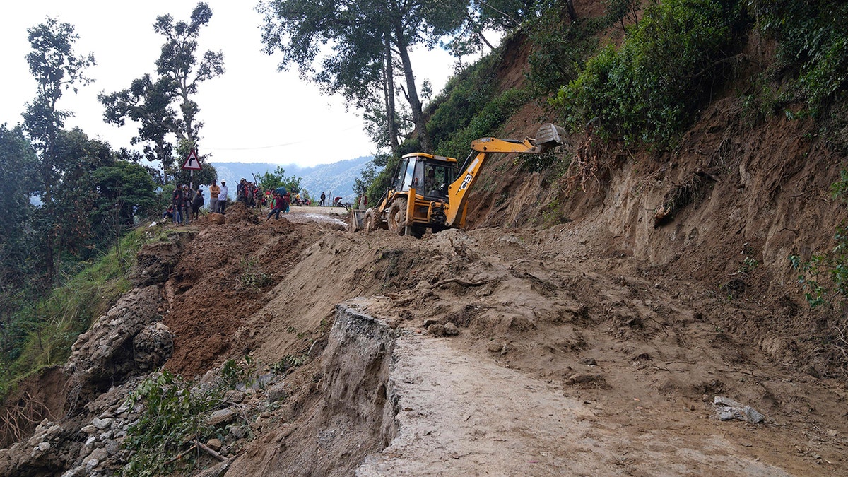 An earthmover helps clear a road affected by landslide after heavy rainfall in Dipayal Silgadhi, Nepal, on Thursday.