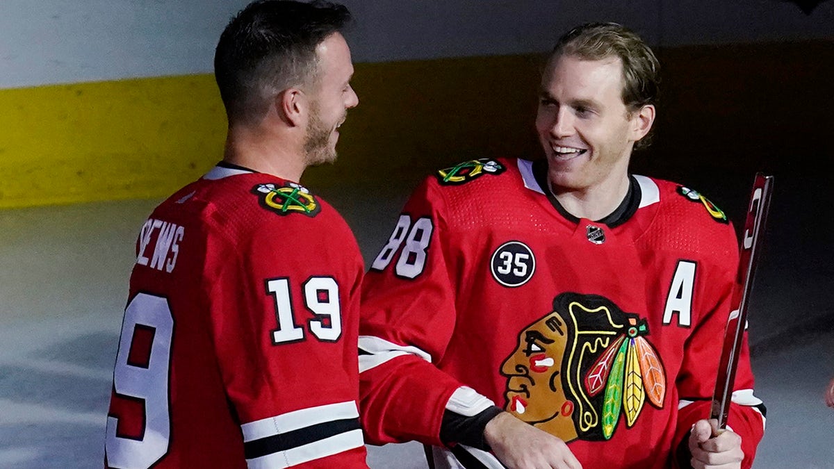 Chicago Blackhawks right wing Patrick Kane, right, smiles as he is joined by center Jonathan Toews while being honored for his 1,000th career NHL hockey game, which happened in March, before the team's game against the Vancouver Canucks in Chicago, Thursday, Oct. 21, 2021. 