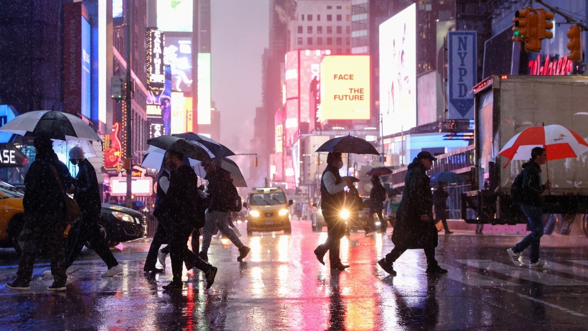 people crossing thoroughfare astatine nighttime portion it rains