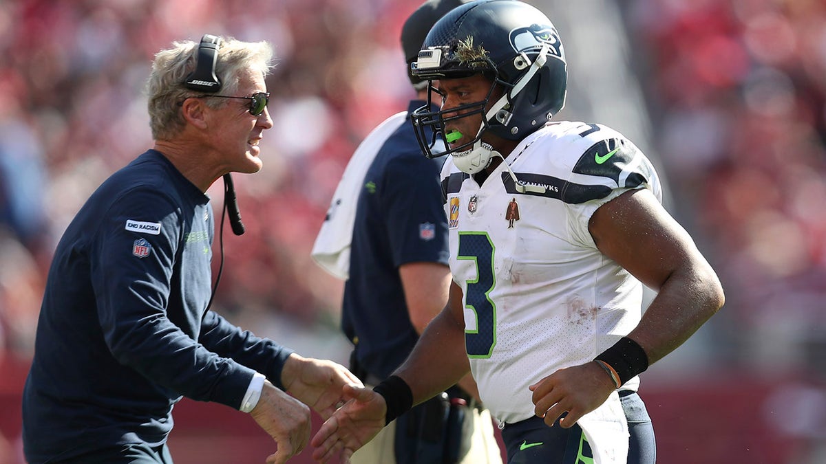 Seattle Seahawks quarterback Russell Wilson is congratulated by head coach Pete Carroll after scoring against the San Francisco 49ers during the second half of an NFL football game in Santa Clara, California, Sunday, Oct. 3, 2021.