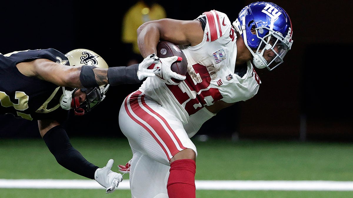 New York Giants running back Saquon Barkley (26) scores on a touchdown reception against New Orleans Saints cornerback Marshon Lattimore in the second half of an NFL football game in New Orleans, Sunday, Oct. 3, 2021.