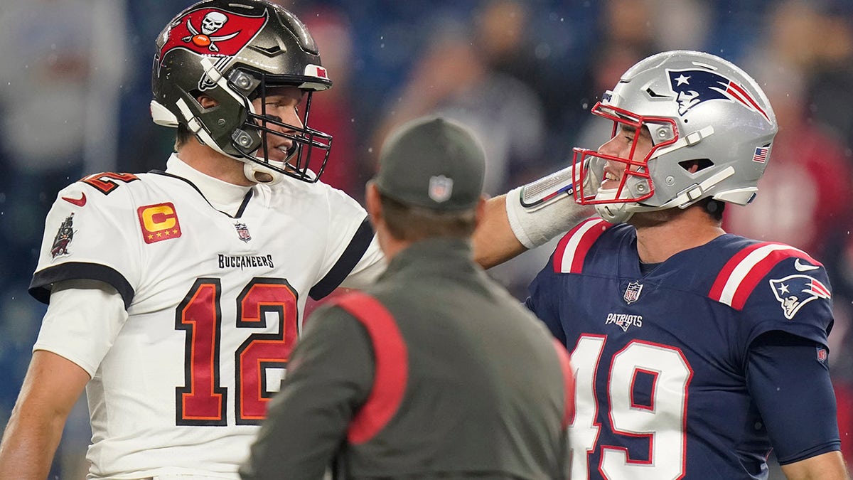 Tampa Bay Buccaneers quarterback Tom Brady (12) meets with New England Patriots long snapper Joe Cardona (49) before a game between the New England Patriots and Tampa Bay Buccaneers, Sunday, Oct. 3, 2021, in Foxborough, Mass.