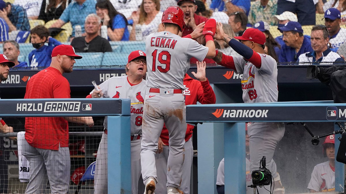 St. Louis Cardinals' Tommy Edman (19) celebrates in the dugout after scoring off of a wild pitch thrown by Los Angeles Dodgers starting pitcher Max Scherzer during the first inning of a National League Wild Card playoff baseball game Wednesday, Oct. 6, 2021, in Los Angeles.