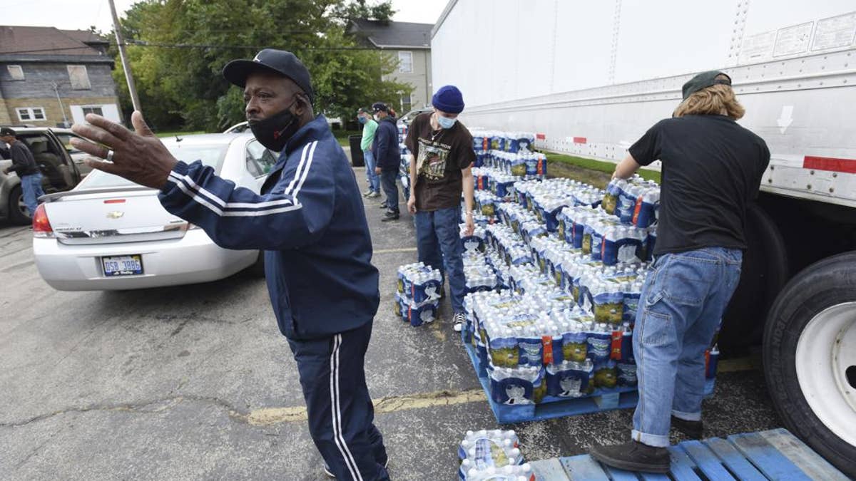 Dwayne Yarbrough directs traffic as volunteers distribute cases of bottled water to residents at God's Household of Faith, Friday, Oct. 15, 2021, in Benton Harbor, Michigan. Gov. Gretchen Whitmer on Thursday ordered a "whole-of-government" response to elevated levels of lead in tap water in the southwestern Michigan city of Benton Harbor and vowed to accelerate the replacement of its lead pipes. (Don Campbell/The Herald-Palladium via AP)