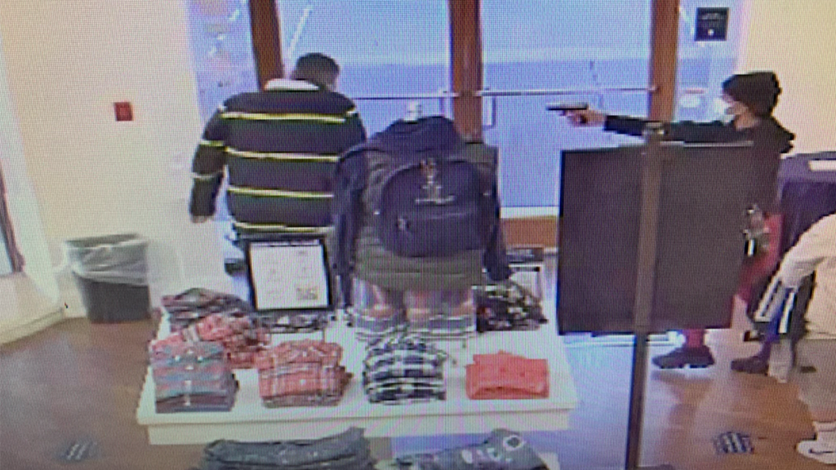 A suspect pointing a gun at an employee.