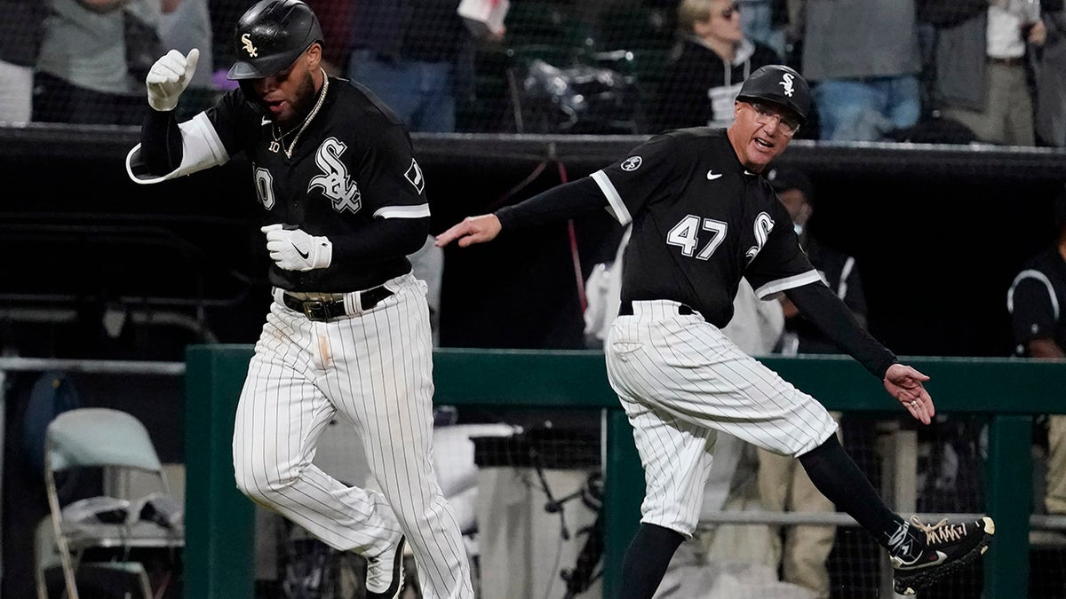 The Chicago White Sox’ Yoán Moncada, left, celebrates with third base coach Joe McEwing after hitting a two-run home run during the eighth inning of a baseball game against the Detroit Tigers in Chicago, Saturday, Oct. 2, 2021.
