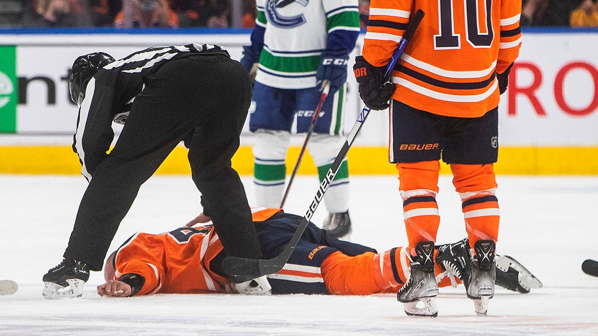 Edmonton Oilers' Zack Kassian (44) lies on the ice after a fight with Vancouver Canucks' Zack MacEwen (71) during third-period preseason NHL hockey game action in Edmonton, Alberta, Thursday, Oct. 7, 2021.