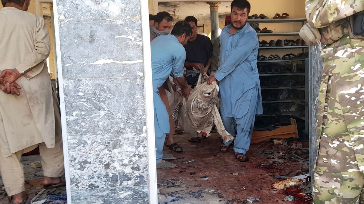 People carry the body of a victim following a bombing in Kunduz province, northern Afghanistan, Friday, Oct. 8, 2021. A powerful explosion in a mosque frequented by a Muslim religious minority in northern Afghanistan on Friday has left several casualties, witnesses and the Taliban's spokesman said. (AP Photo/Abdullah Sahil)