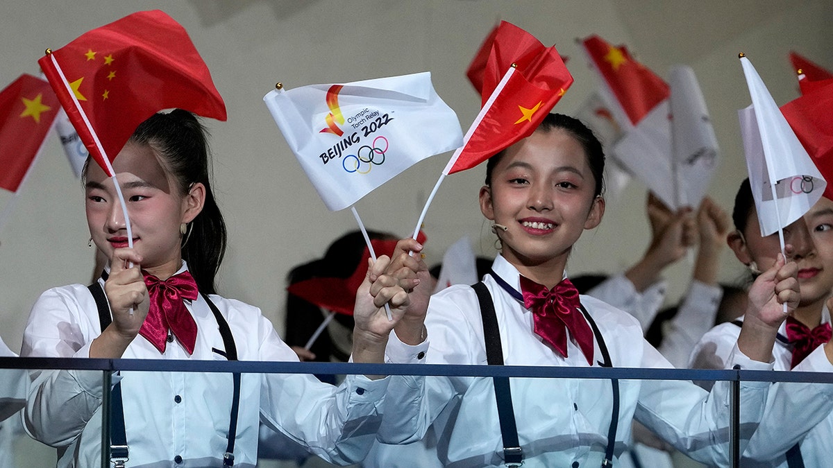 Children wave national flags and Beijing 2022 Winter Olympic Games flags during a welcome ceremony for the Frame of Olympic Winter Games Beijing 2022, held at the Olympic Tower in Beijing, Wednesday, Oct. 20, 2021. (AP Photo/Andy Wong)