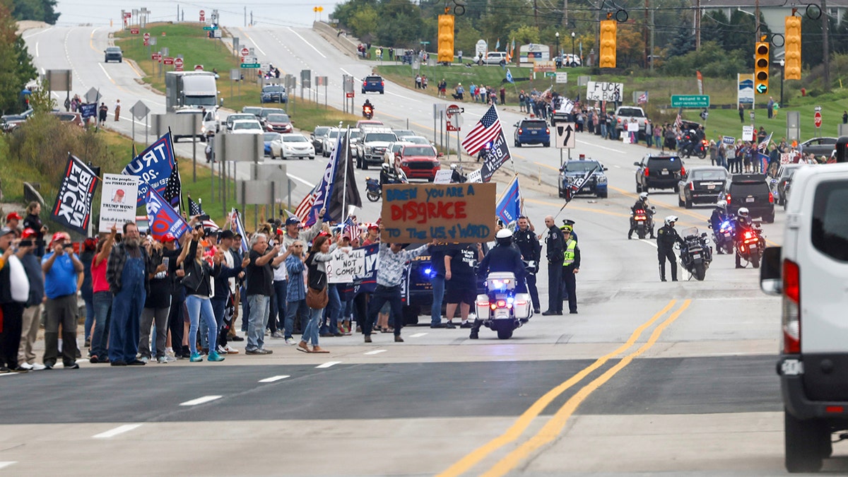 Anti-Biden demonstrators spill out into the street as they jeer the president's motorcade after a visit to the International Union of Operating Engineers Local 324 training facility in Howell, Michigan, Oct. 5, 2021.