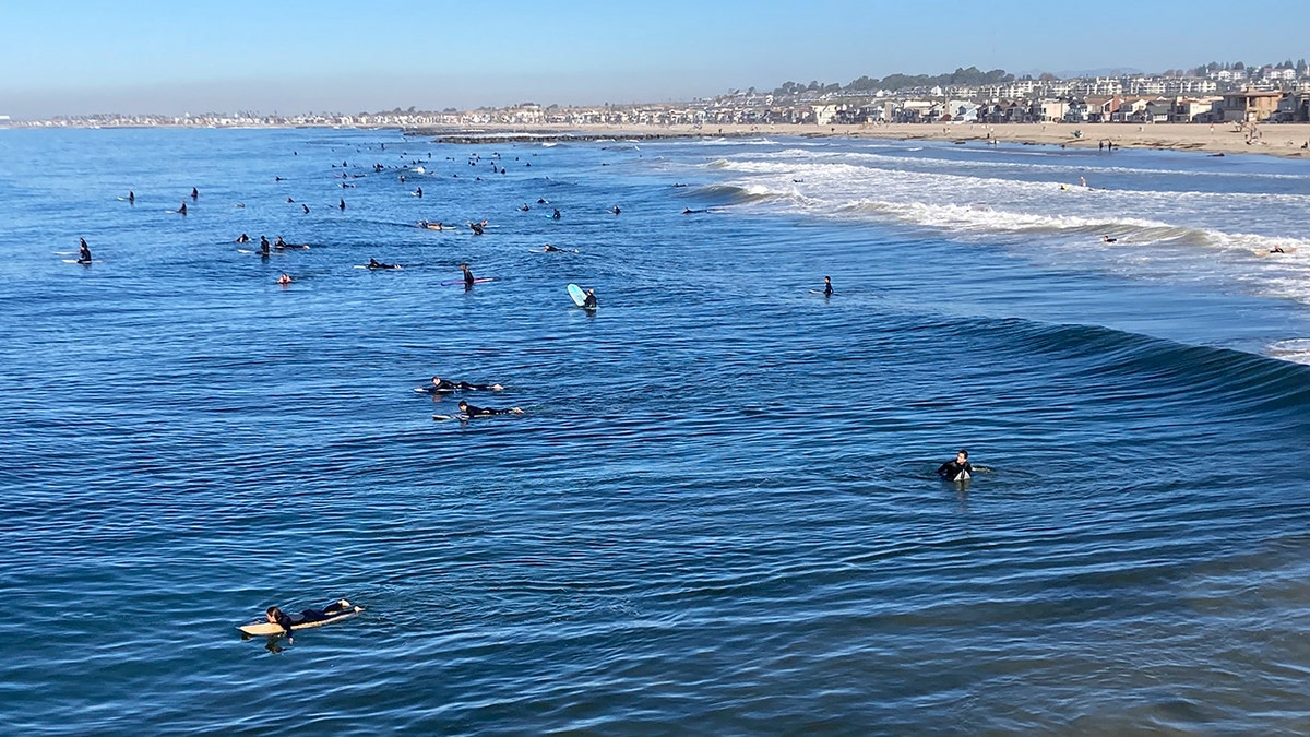 Surfers head out in Newport Beach, California, on Wednesday.