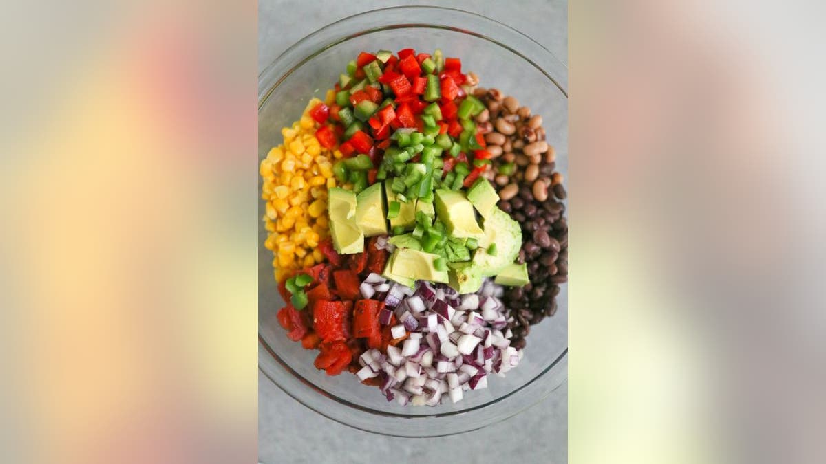 The Cowboy Caviar recipe includes red onions, corn, beans, fire-roasted garlic tomatoes, bell peppers, avocadoes, jalapeño and cilantro.