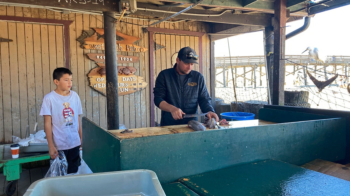 Scott Breneman, owner of West Caught Fish, slices fish for a customer at a market in Newport Beach, California on Wednesday.