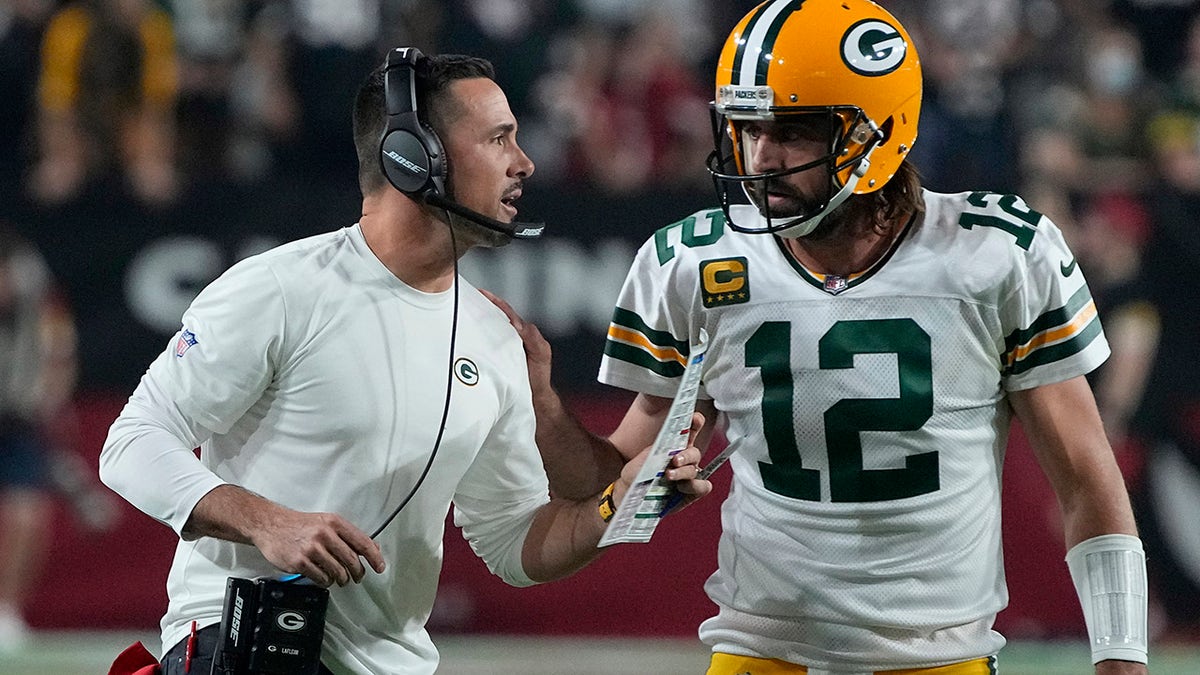 Green Bay Packers head coach Matt LaFleur talks with quarterback Aaron Rodgers (12) during the first half of an NFL football game against the Arizona Cardinals, Thursday, Oct. 28, 2021, in Glendale, Ariz.
