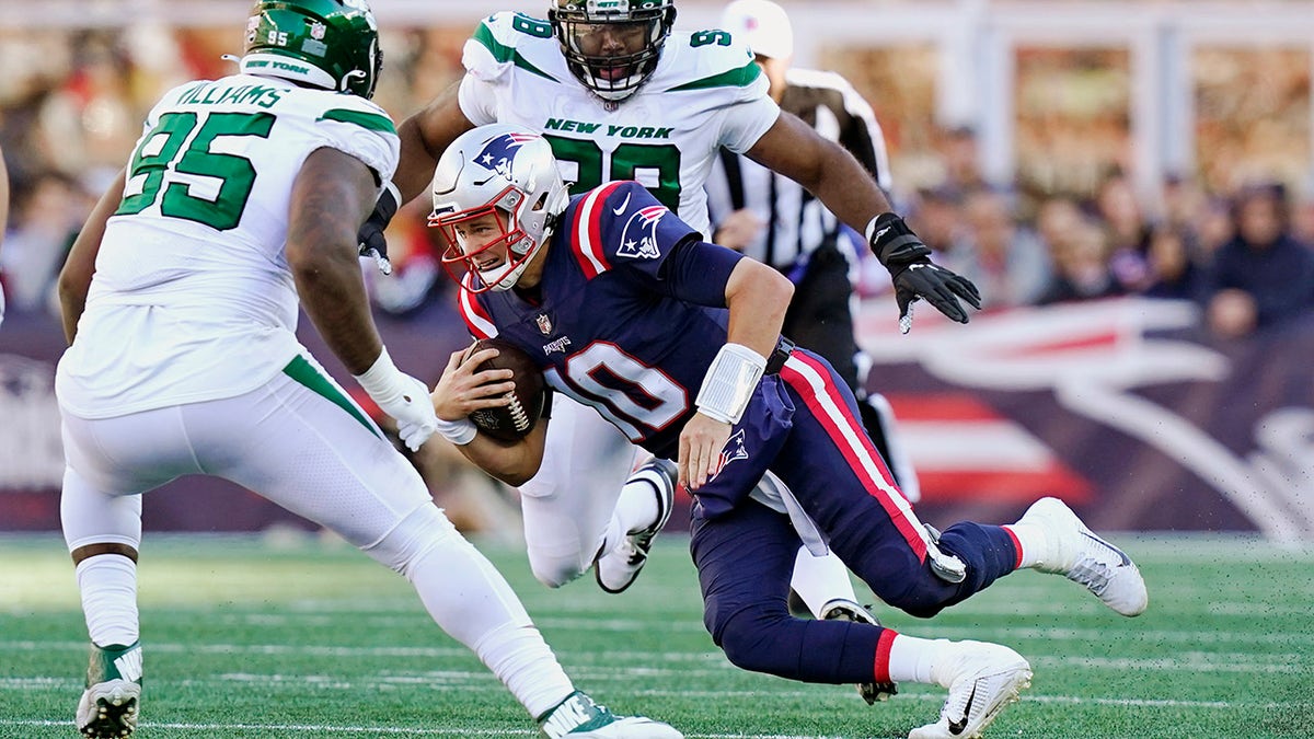 New England Patriots quarterback Mac Jones (10) tries to thread between New York Jets Quinnen Williams (95) and Sheldon Rankins, rear, during the second half of a game, Sunday, Oct. 24, 2021, in Foxborough, Mass. 