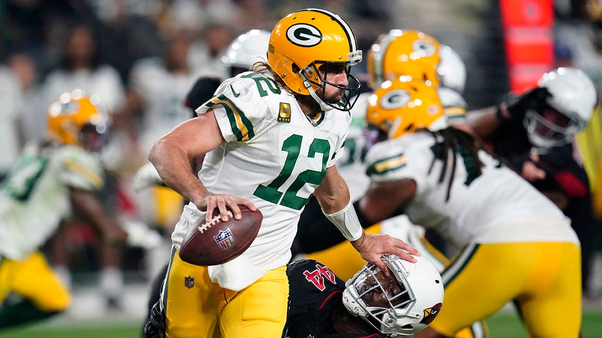 Green Bay Packers quarterback Aaron Rodgers (12) pushes down Arizona Cardinals linebacker Markus Golden (44) during the first half of an NFL football game, Thursday, Oct. 28, 2021, in Glendale, Ariz.