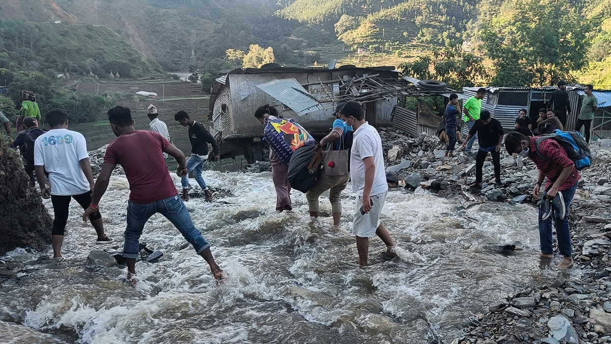 People wade past a flooded area in Dipayal Silgadhi, Nepal, on Thursday.