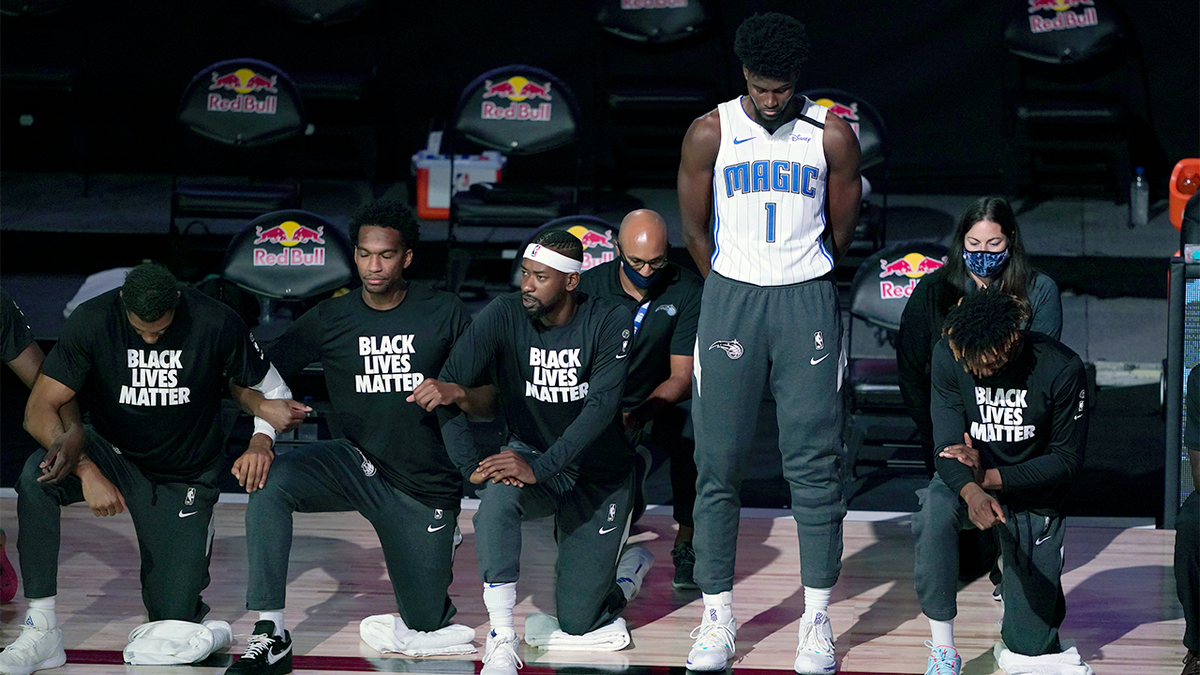 Jonathan Isaac of the Orlando Magic stands as others kneel