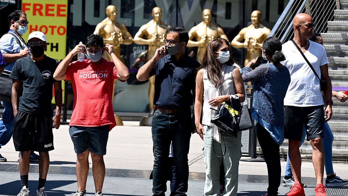People wearing masks wait to cross the street in Hollywood, California.