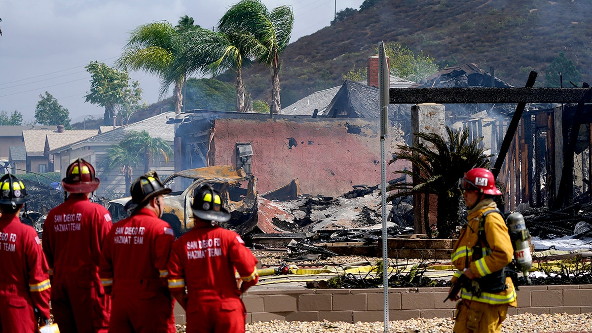 Fire crews work the scene of a small plane crash, Monday, Oct. 11, 2021, in Santee, California. At least two people were killed and two others were injured when the plane crashed into a suburban Southern California neighborhood, setting two homes ablaze, authorities said. (AP Photo/Gregory Bull)