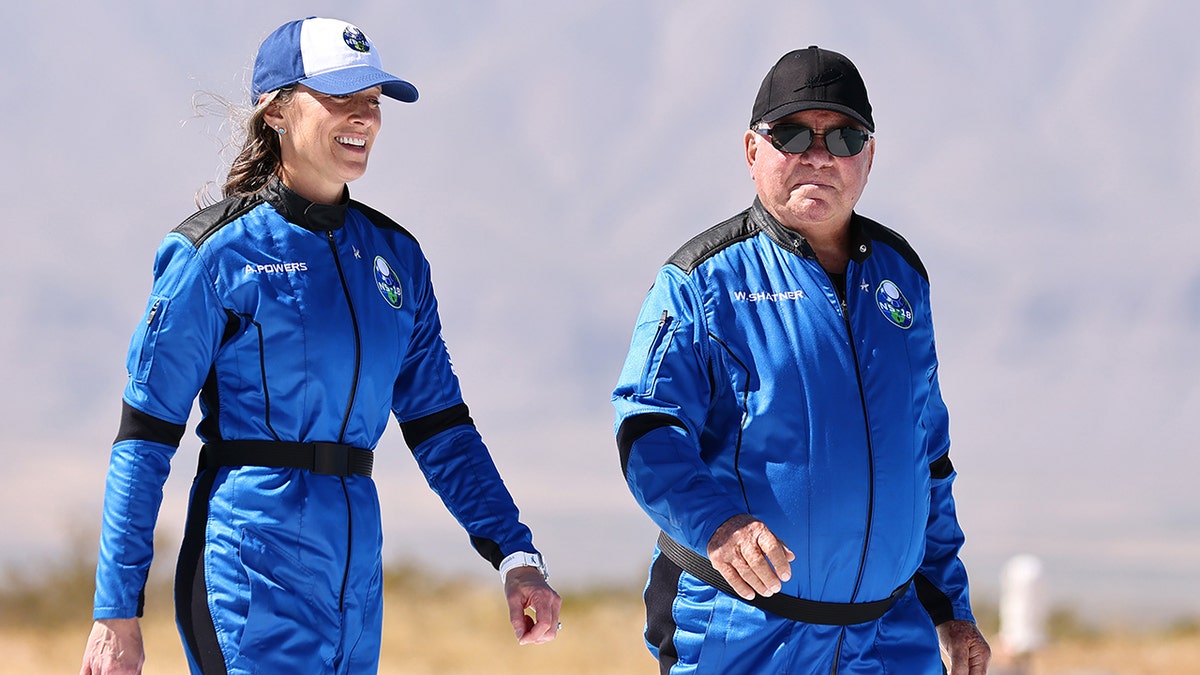 Blue Origin vice president of mission and flight operations Audrey Powers (L) walks with Star Trek actor William Shatner to a media availability on the landing pad of Blue Origin’s New Shepard after they flew into space on October 13, 2021 near Van Horn, Texas. Shatner became the oldest person to fly into space on the ten minute flight. They flew aboard mission NS-18, the second human spaceflight for the company which is owned by Amazon founder Jeff Bezos.?