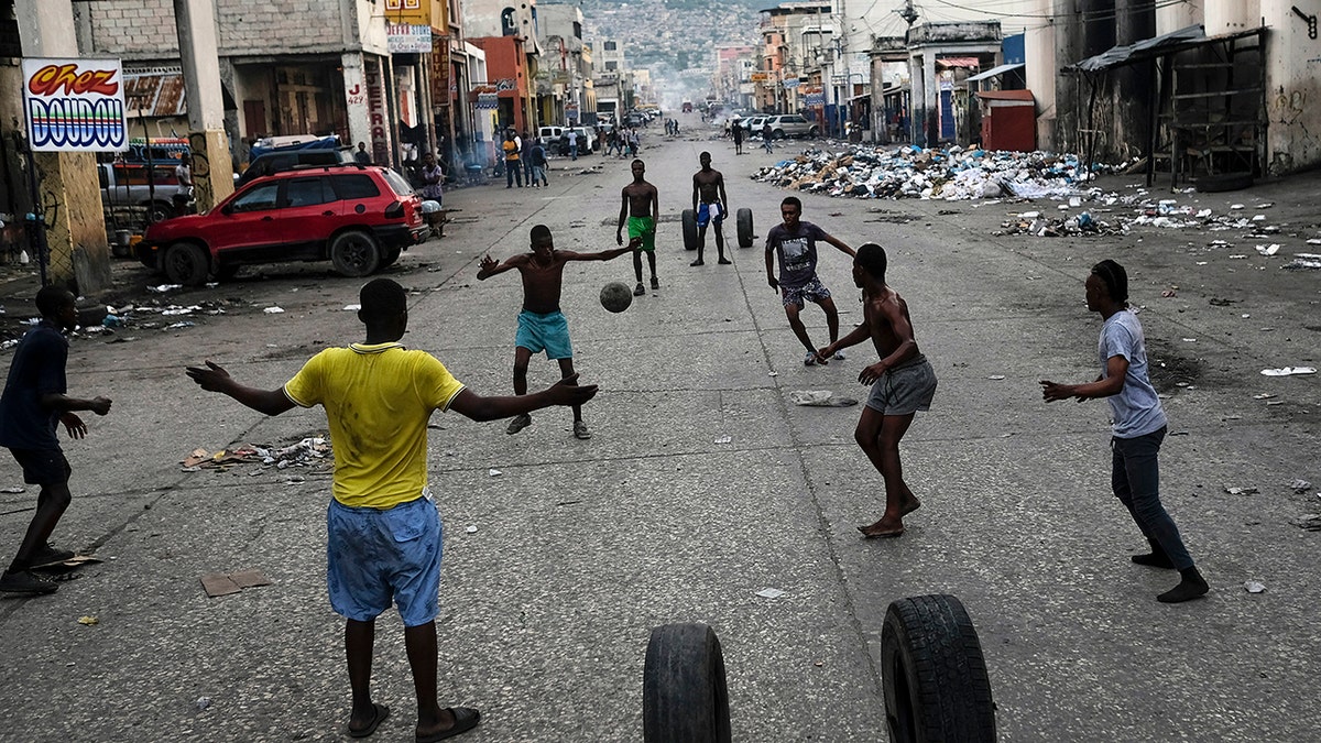 Youths play soccer next to businesses that are closed due to a general strike in Port-au-Prince, Haiti, on Monday.