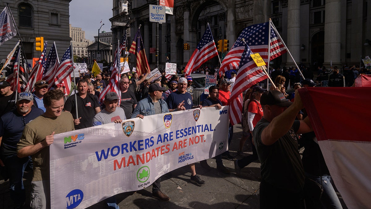Municipal workers hold placards and shout slogans as they march during a protest against the COVID-19 vaccine mandate in New York on Oct. 25.
