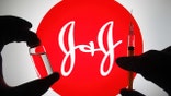 UKRAINE - 2021/04/27: In this illustrative image, silhouette of hands in medical gloves hold a medical syringe and a vial in front of Johnson &amp; Johnson (J&amp;J) logo. (Photo Illustration by Pavlo Gonchar/SOPA Images/LightRocket via Getty Images)