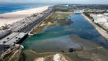 An aerial photo shows floating barriers known as booms to try to stop further incursion into the Wetlands Talbert Marsh after an oil spill in Huntington Beach, Calif., on Huntington Beach, Calif., on Monday, Oct. 4, 2021. A major oil spill off the coast of Southern California fouled popular beaches and killed wildlife while crews scrambled Sunday, to contain the crude before it spread further into protected wetlands. (AP Photo/Ringo H.W. Chiu)