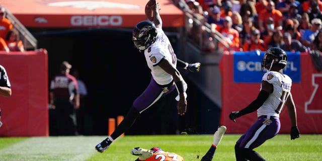 Oct 3, 2021; Denver, Colorado, USA; Baltimore Ravens quarterback Lamar Jackson (8) leaps over Denver Broncos cornerback Kyle Fuller (23) in the second quarter at Empower Field at Mile High.