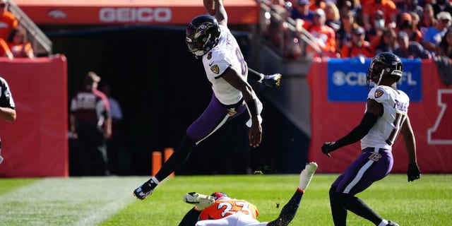 Baltimore Ravens quarterback Lamar Jackson (8) leaps over Denver Broncos cornerback Kyle Fuller (23) in the second quarter at Empower Field at Mile High. Mandatory Credit: Ron Chenoy-USA TODAY Sports