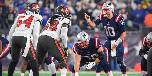 New England Patriots quarterback Mac Jones (10) sets the play against Tampa Bay Buccaneers outside linebacker Lavonte David (54) and defensive tackle Rakeem Nunez-Roches (56) during the first quarter at Gillette Stadium.