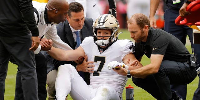 Oct 10, 2021; Landover, Maryland, USA; New Orleans Saints wide receiver Taysom Hill (7) is helped to his feet after being injured against the Washington Football Team during the second quarter at FedExField. Mandatory Credit: Geoff Burke-USA TODAY Sports