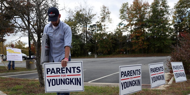 Tristan Thorgersen puts pro-Youngkin signs up as people gather to protest different issues, including the school board’s handling of a sexual assault that happened in a school bathroom in May, vaccine mandates and critical race theory during a Loudoun County School Board meeting in Ashburn, バージニア, 10月. 26, 2021. 