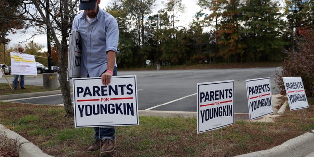 Tristan Thorgersen puts pro-Youngkin signs up as people gather to protest different issues including the board’s handling of a sexual assault that happened in a school bathroom in May, vaccine mandates and critical race theory during a Loudoun County School Board meeting in Ashburn, Virginia, U.S., October 26, 2021. Picture taken October 26, 2021. REUTERS/Leah Millis