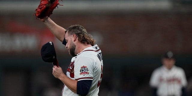Atlanta Braves relief pitcher A.J. Minter wipes his face after giving up a 2-RBI double to Houston Astros' Marwin Gonzalez during the fifth inning in Game 5 of baseball's World Series between the Houston Astros and the Atlanta Braves Sunday, Oct. 31, 2021, in Atlanta.