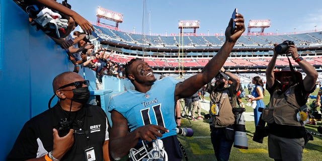 테네시 타이탄스의 리시버 AJ 브라운(11)이 2021년 10월 24일 일요일 테네시주 내슈빌에서 열린 NFL 미식축구 경기에서 타이탄스가 캔자스시티 치프스를 27-3으로 꺾은 후 경기장을 떠나는 팬의 사진을 찍고 있다.