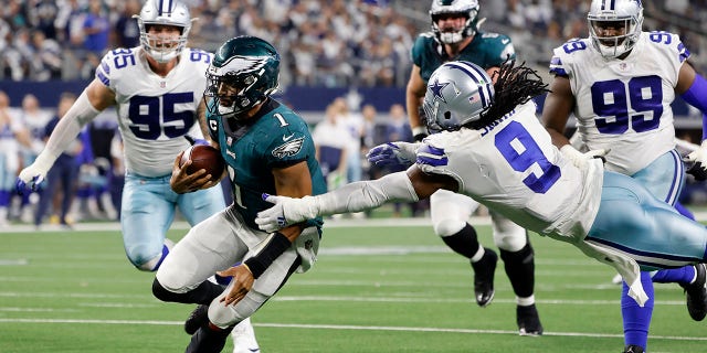 Philadelphia Eagles quarterback Jalen Hurts (1) kicks the ball as Dallas Cowboys linebacker Jaylon Smith (9) tries to make the save in the second half of an NFL football game in Arlington , Texas, Monday, September 27, 2021 (AP Photo / Michael Ainsworth)