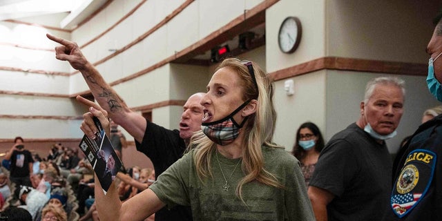 In this Aug. 12, 2021 file photo, protesters against a COVID-19 mandate gesture as they are escorted out of the Clark County School Board meeting at the Clark County Government Center, in Las Vegas.  The nation's school boards are asking President Joe Biden for federal assistance to investigate and stop a growing number of threats made against their members, on Thursday, Sept. 30. 