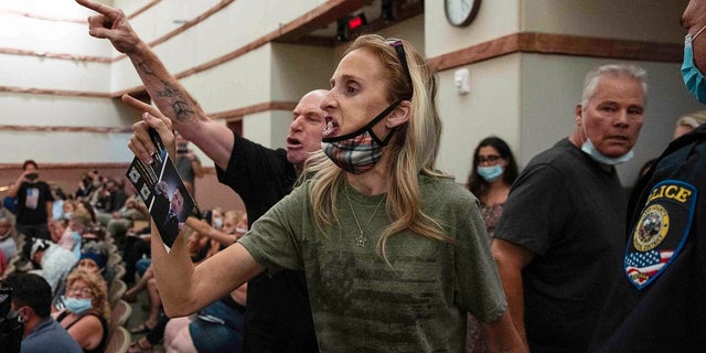 In this Aug. 12, 2021 file photo, protesters against a COVID-19 mandate gesture as they are escorted out of the Clark County School Board meeting at the Clark County Government Center, in Las Vegas.  The nation's school boards are asking President Joe Biden for federal assistance to investigate and stop a growing number of threats made against their members, on Thursday, Sept. 30. 