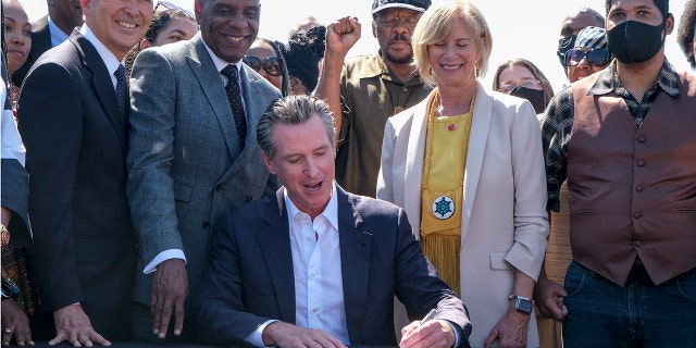 California Gov. Gavin Newsom signs a bill,