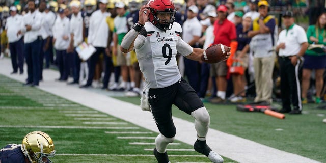 Cincinnati quarterback Desmond Ridder (9) runs in for a touchdown against Notre Dame's JD Bertrand (27) during the second half of an NCAA college football game, Saturday, Oct. 2, 2021, in South Bend, Ind. Cincinnati won 24-13. (AP Photo/Darron Cummings)