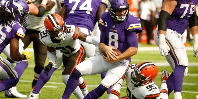 Minnesota Vikings quarterback Kirk Cousins (8) is sacked by Cleveland Browns cornerback Denzel Ward (21) and defensive end Myles Garrett (95) during the second half of an NFL football game, Sunday, Oct. 3, 2021, in Minneapolis. (AP Photo/Bruce Kluckhohn)