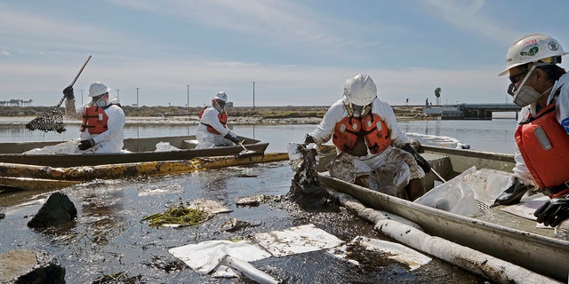 Cleanup contractors deploy skimmers and floating barriers known as booms to try to stop further oil crude incursion into the Wetlands Talbert Marsh in Huntington Beach, Calif., Sunday., Oct. 3, 2021. (AP Photo/Ringo H.W. Chiu)