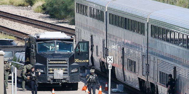 A Tucson Police Department SWAT truck is parked near the last two cars of an Amtrak train in downtown Tucson, Ariz. On Monday.  One person is in police custody after someone opened fire on Monday aboard an Amtrak train parked at the downtown station in the city.  (Mamta Popat / Arizona Daily Star via AP)